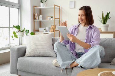 Tablet bilgisayar evde kanepede kullanan genç kadın