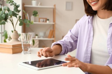 Masada tablet bilgisayar kullanan genç bir kadın, yakın plan.