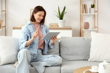 Tablet bilgisayar evde kanepede kullanan genç kadın