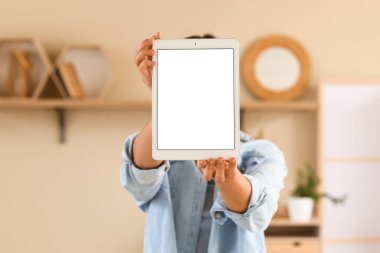 Evde boş tablet bilgisayarı olan genç bir kadın, yakın çekim.