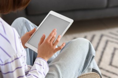 Evde boş tablet bilgisayar kullanan genç bir kadın, yakın çekim.