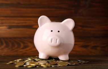 Ahşap arka planda bozuk paraları olan kumbara.