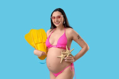 Mavi arka planda deniz yıldızları ve paletleri olan hamile bir kadın. Seyahat kavramı