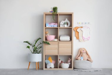 Rafların, oyuncakların ve bebek kıyafetlerinin asılı olduğu şık bir çocuk odası.