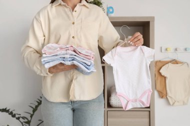 Bebek elbiseli genç anne şık çocuk odasında, yakın plan.