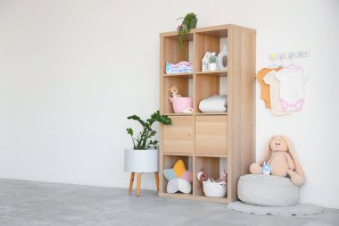 Rafların, oyuncakların ve bebek kıyafetlerinin asılı olduğu şık bir çocuk odası.