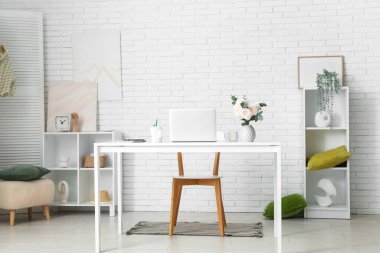 Modern dizüstü bilgisayarı ve hafif ev ofisinde güzel çiçekleri olan şık çalışma alanı.