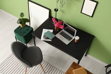 Modern dizüstü bilgisayarı ve güzel çiçekleri olan şık bir çalışma alanı.