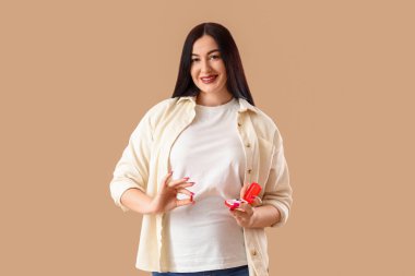 Bej arka planda hap kutusu olan güzel hamile bir kadın.