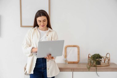 Gözlüklü güzel bir kadın evde dizüstü bilgisayar kullanıyor.