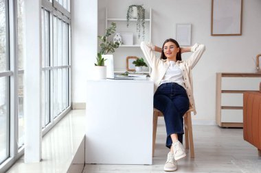 Evdeki masanın yanında oturan güzel genç bayan.