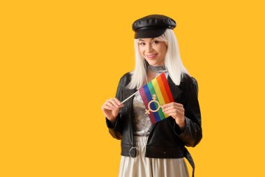 Sarı arka planda gökkuşağı bayrağı ve transseksüel sembolü olan güzel bir genç kadın. LGBT kavramı