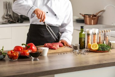 Erkek aşçı mutfakta et pişiriyor.