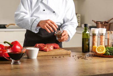 Erkek aşçı mutfakta çiğ et yiyor.