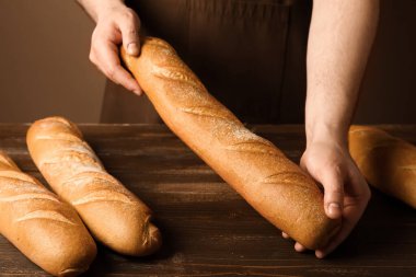 Kahverengi arka planda taze baget yiyen adam.