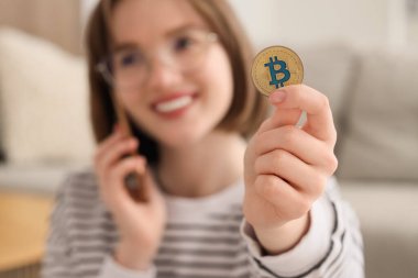 Bitcoin 'li genç bir kadın cep telefonuyla konuşuyor, yakın plan.