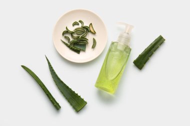 Beyaz arka planda aloe vera yapraklı bir şişe kozmetik ürünü.