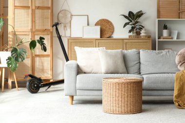 Oturma odasının içinde elektrikli scooter ve kanepe var.