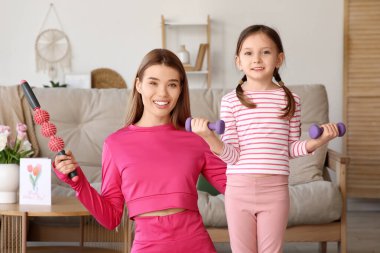 Sportif genç anne ve evde spor aletleri olan sevimli küçük kızı. Anneler Günü kutlaması