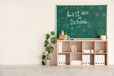 Okulun Son Günü yazılı karatahta, sınıfta çizimler ve raf ünitesi