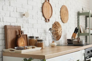 Mutfaktaki beyaz tuğla duvarın yanındaki tezgahta yemek kesme tahtaları.