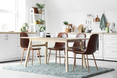 Mutfağın içinde tezgah, mutfak gereçleri ve yemek masası var.