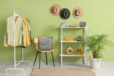 Elbise askısı, sandalye ve raf ünitesi olan bir stilistin stüdyosu.