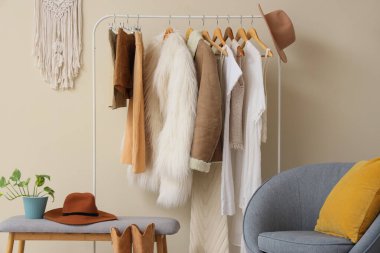 Moda stüdyosunun içinde elbise askısı, koltuk ve yumuşak bank var.