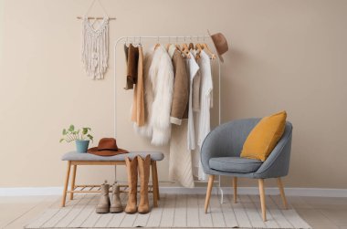 Moda stüdyosunun içinde elbise askısı, koltuk ve yumuşak bank var.