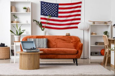 ABD bayrağı, kanepesi ve raf üniteleriyle aydınlık oturma odasının içinde.
