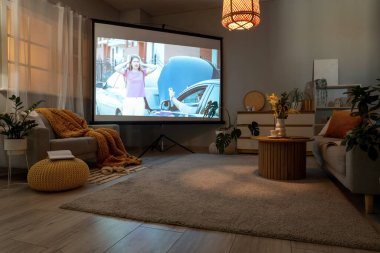 Gri kanepesi, sehpası ve modern projektörü olan şık bir oturma odası.
