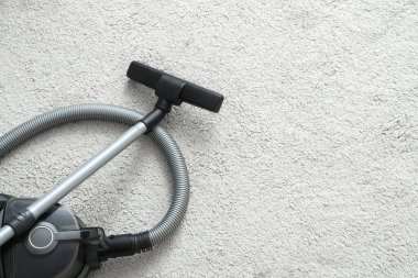 Gri halıda modern elektrikli süpürge, üst manzara.