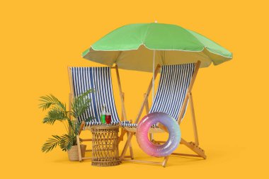 Şemsiyeli çizgili sandalyeler, şişirilebilir yüzük ve sarı arka planda kokteyl bardakları.