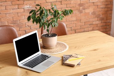 Boş dizüstü bilgisayar ve yemek masasının üzerine yerleştirilmiş defterler.