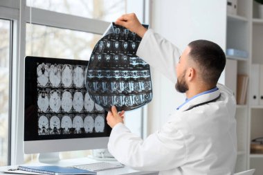 Erkek doktor, klinikte leğen kemiğinin MRI taramasını inceliyor.