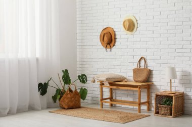 Odanın içindeki beyaz tuğla duvarın yanındaki bankta, masada ve saksıda.