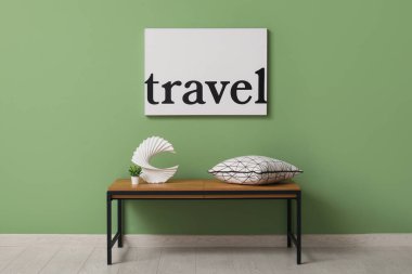 Yastıklı bank, heykelcik ve odanın içindeki yeşil duvarın yanındaki saksı bitkisi.