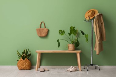 Koridorun iç tarafındaki yeşil duvarın yanındaki bank ve bitkiler.