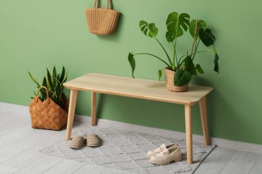 Koridorun iç tarafındaki yeşil duvarın yanındaki bank ve bitkiler.