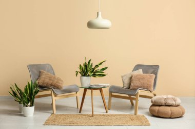 İçinde sandalyeler, masa, puf ve sansevieria bitkileri olan bir oda.