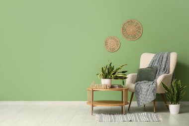 Sansevieria bitkileri, koltuk ve yeşil duvarın yanındaki masa.