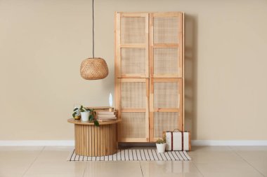 Masa, dolap, bavul ve odanın içindeki bej duvarın yanında kitaplar.