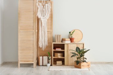 Katlanan ekran, çekmece sandığı ve odanın içindeki beyaz duvarın yanındaki kitaplar.