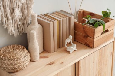 Kutulu çekmeceler, dekoratif şişeler ve beyaz duvarın yanındaki kitaplar, yakın plan.