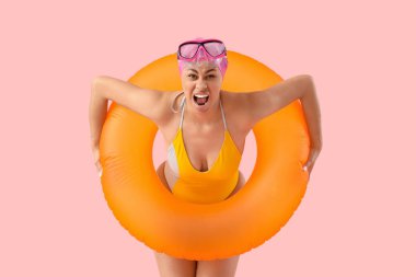 Pembe arka planda bağıran şişme yüzüklü Afro-Amerikalı bir kadın yüzücü.