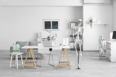 Masada insan iskeleti modeli ve modern dizüstü bilgisayarı olan hafif bir hastane.