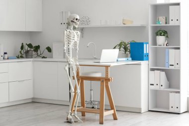 Masada insan iskeleti modeli ve modern dizüstü bilgisayarı olan hafif bir hastane.