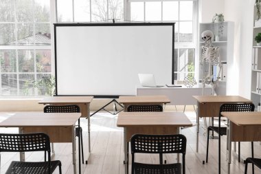 İnsan iskeleti modeli, masa ve projektör ekranlı modern dizüstü bilgisayarlı hafif hastane konferans salonu.