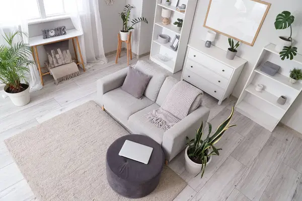 Gri kanepe, puf ve raf üniteli oturma odasının içi.