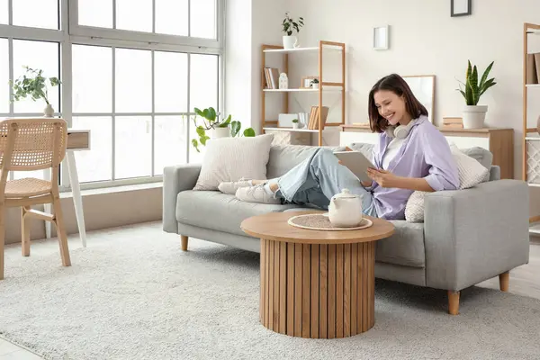 Tablet bilgisayar evde kanepede kullanan genç kadın